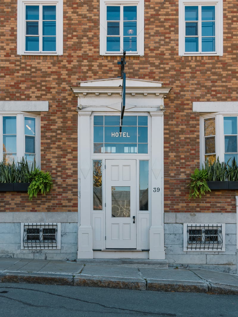 A brick hotel facade with a white entrance door and steps.