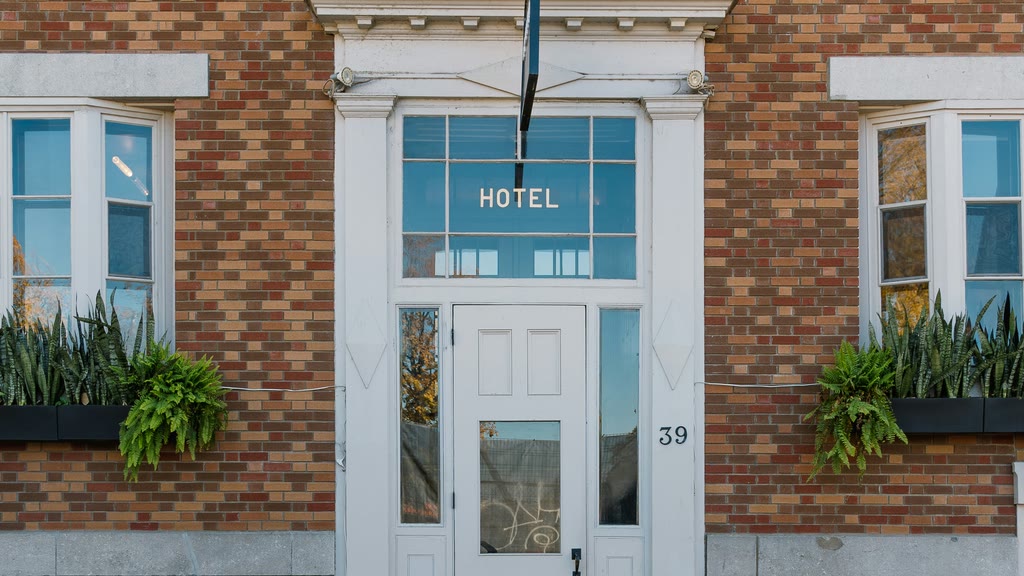 A brick hotel facade with a white entrance door and steps.