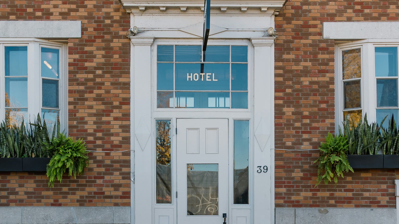 A brick hotel facade with a white entrance door and steps.