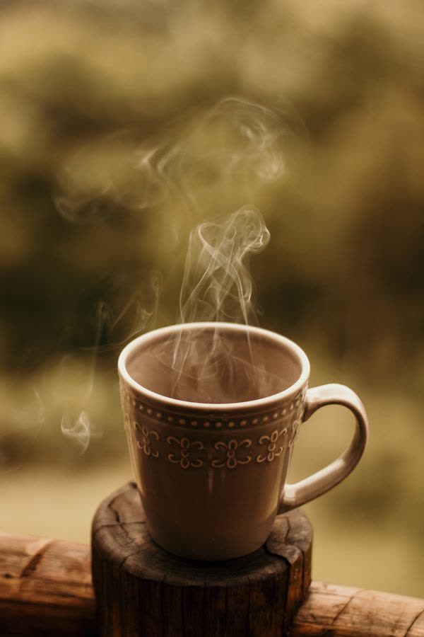 Steaming mug of coffee on a porch rail
