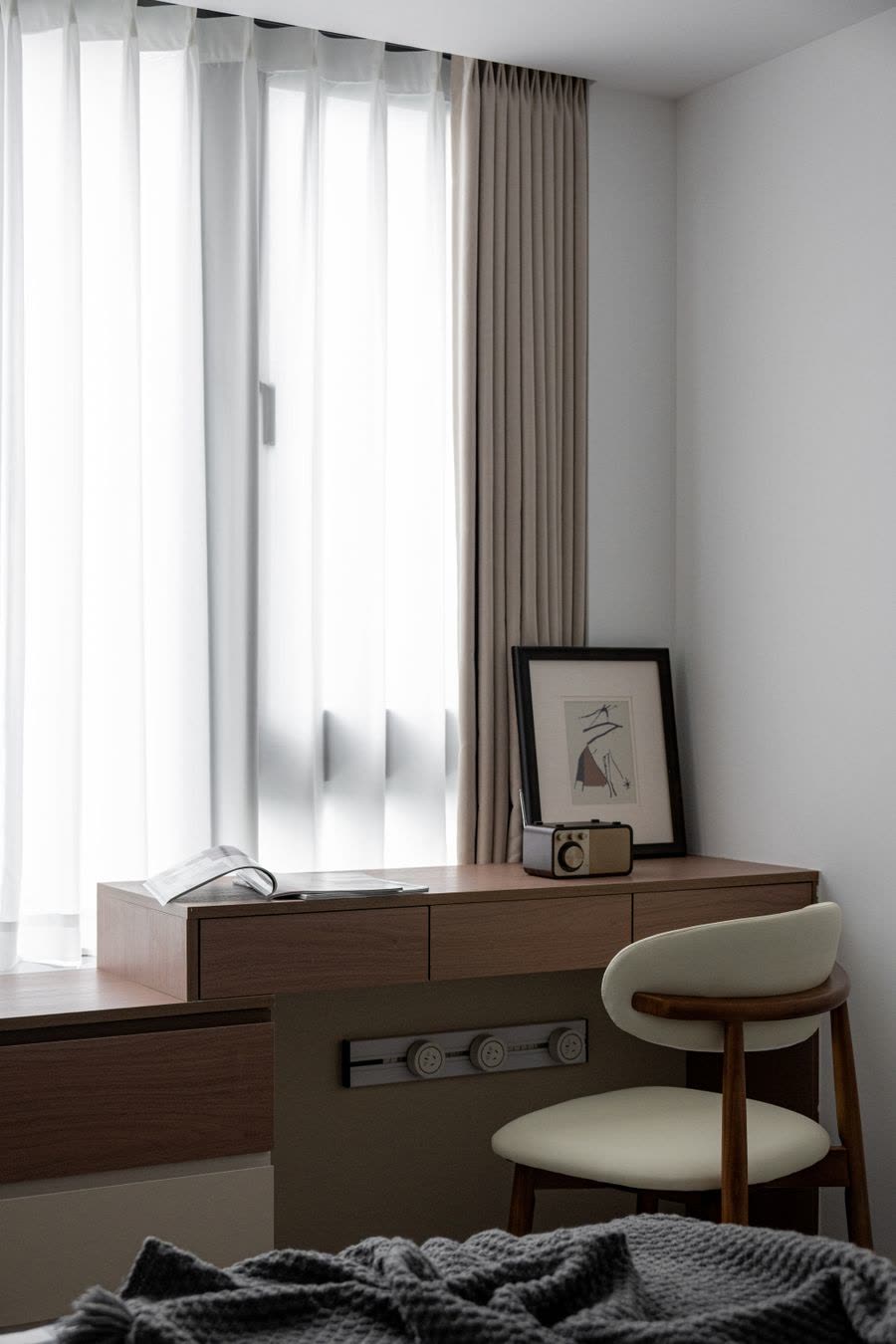 Wooden work desk and chair beside a curtained window