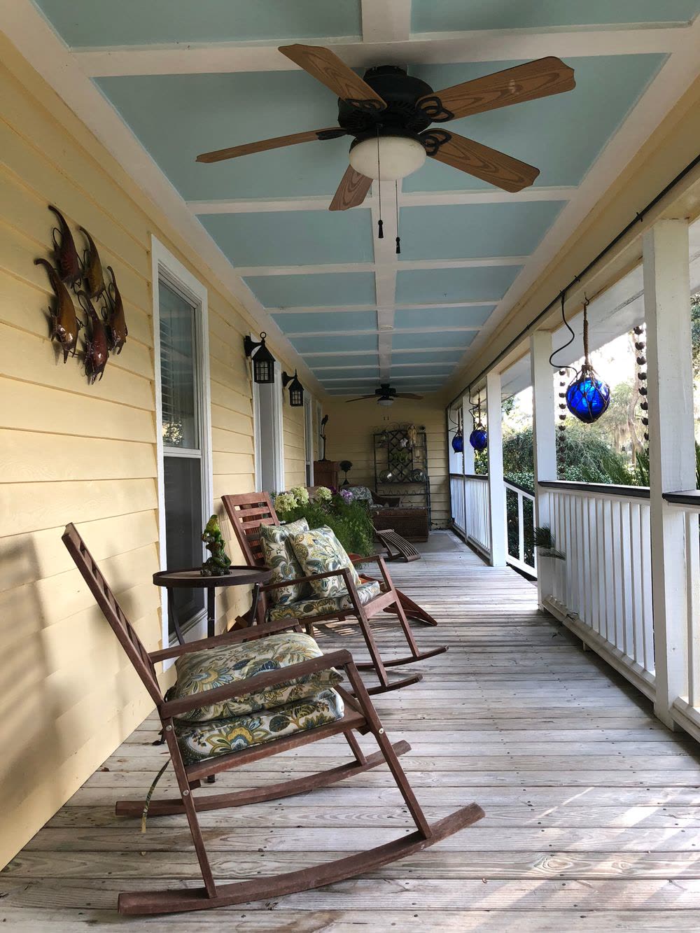 Long covered front porch with rocking chairs and a ceiling fan