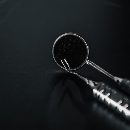 A mouth mirror and handpiece on a dark tray