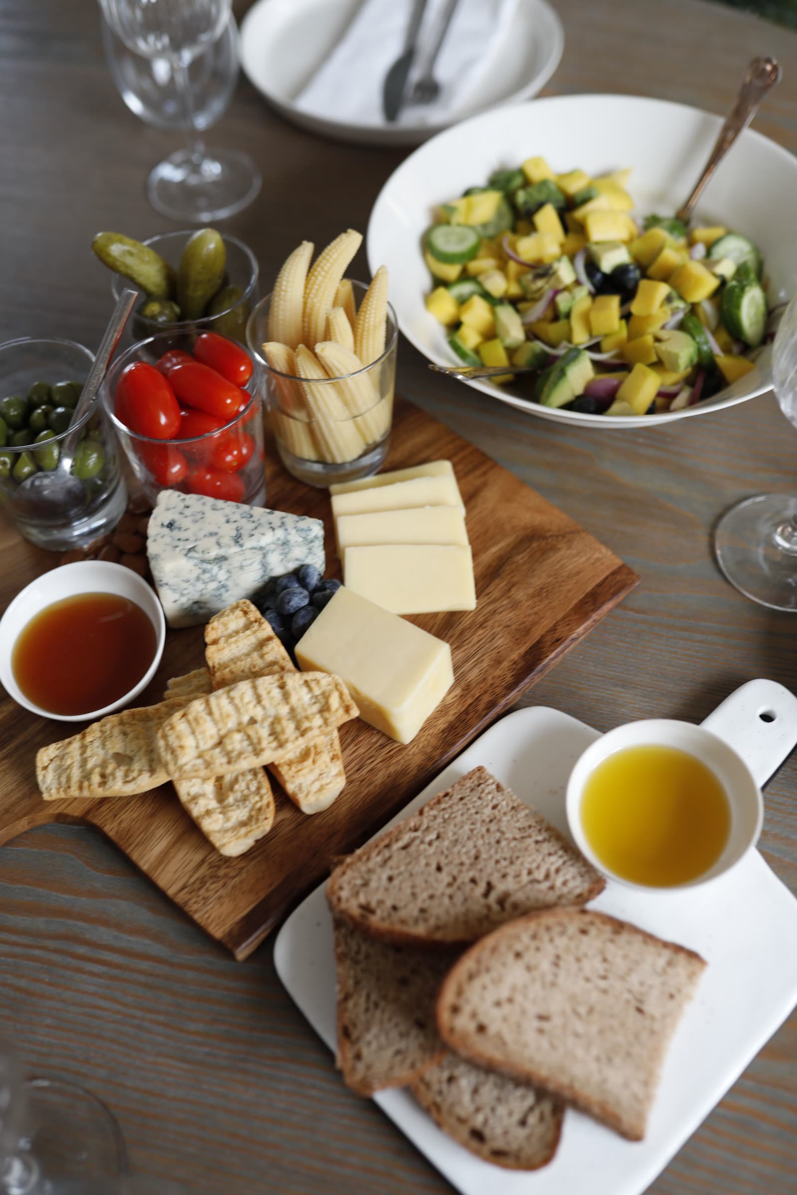A cheese and charcuterie board with olives, cured meats and cocktails