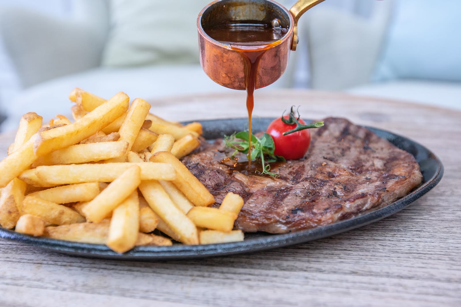 Steak frites with maître d'hôtel butter, hand-cut fries and a ramekin of sauce on a blue-rimmed plate