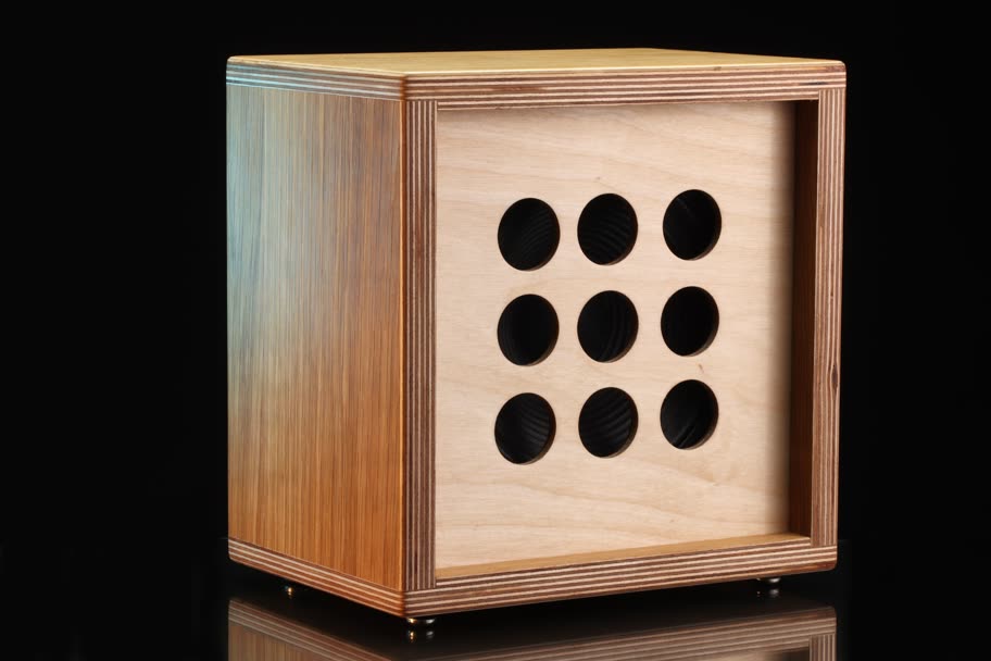 An unfinished birch plywood cabinet with nine round holes on a dark background