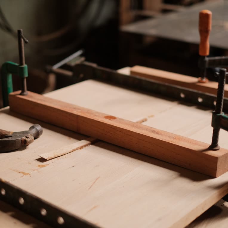 Wooden panels held in bar clamps on a workbench