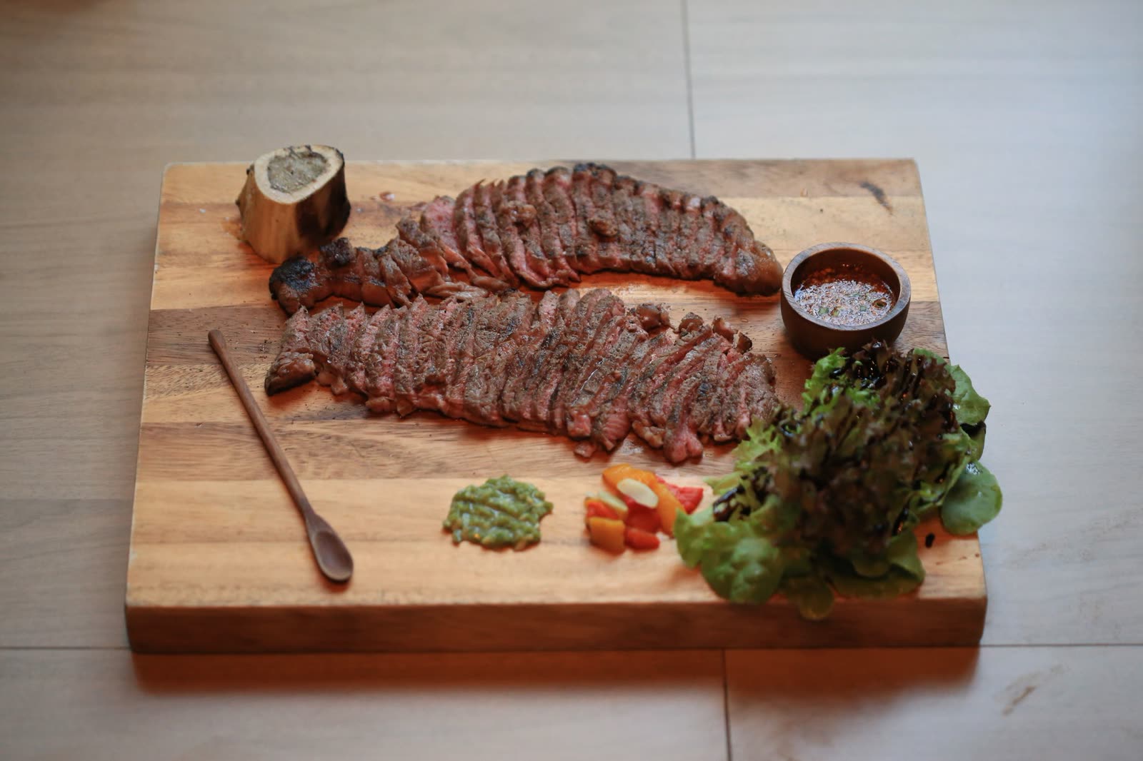 A sliced porterhouse served on a warm platter with béarnaise