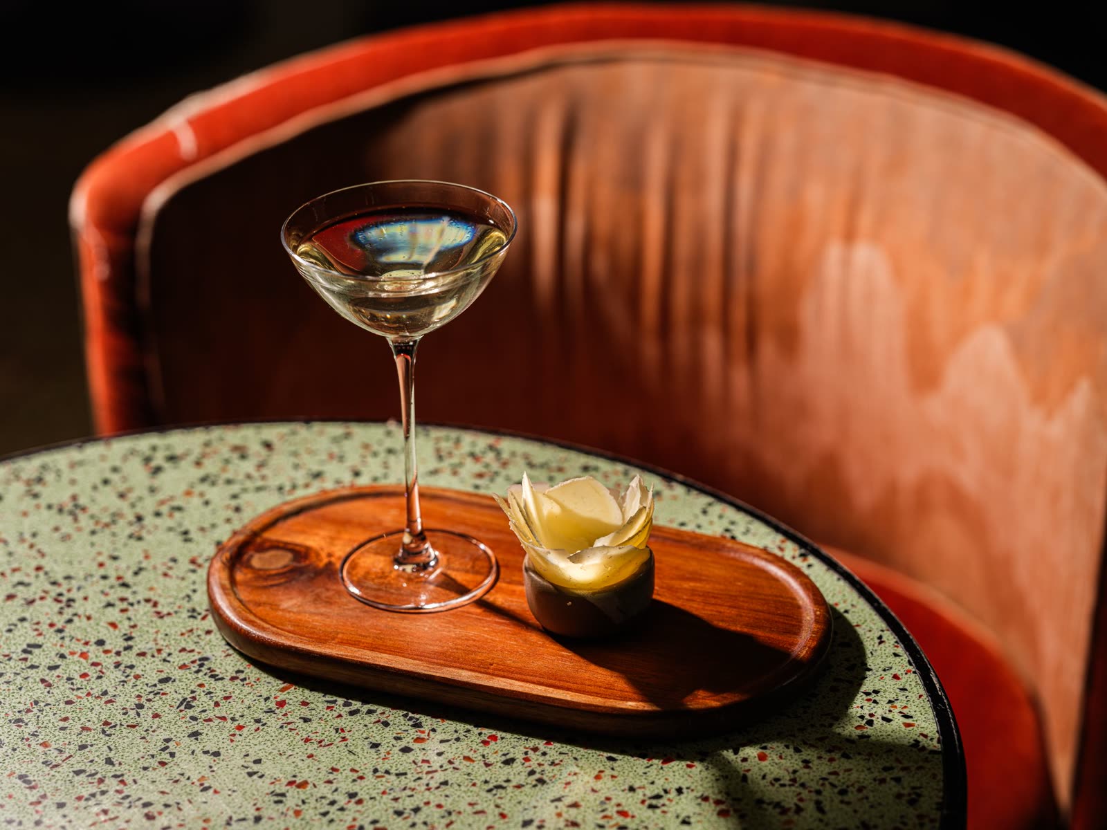 A candlelit table at COPPER LANTERN with a martini being lifted from a shared spread
