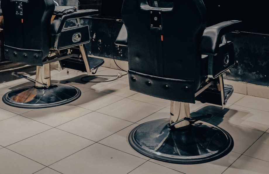 Two black barber chairs on a tiled floor