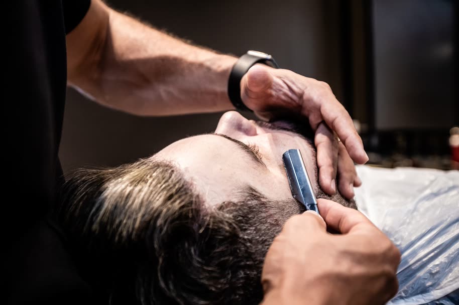 Barber lining up a beard with a straight razor