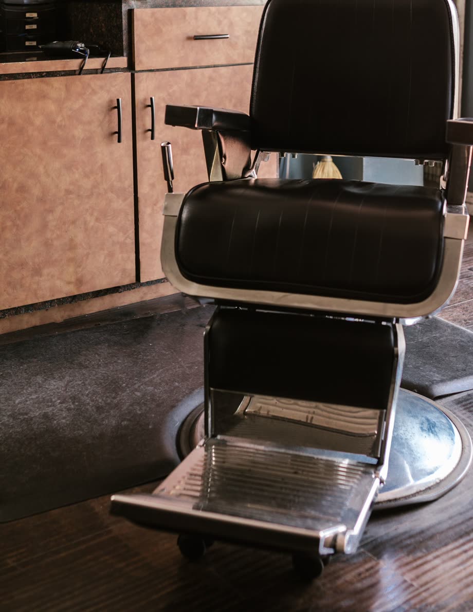 Black leather barber chair beside a wooden counter