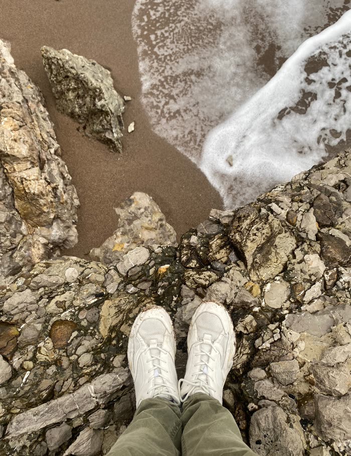 White sneakers standing on wet rock above the waterline