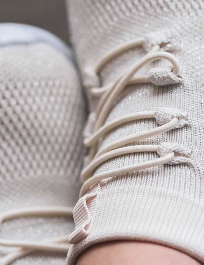 Close view of an oat-colored knit upper and its laces