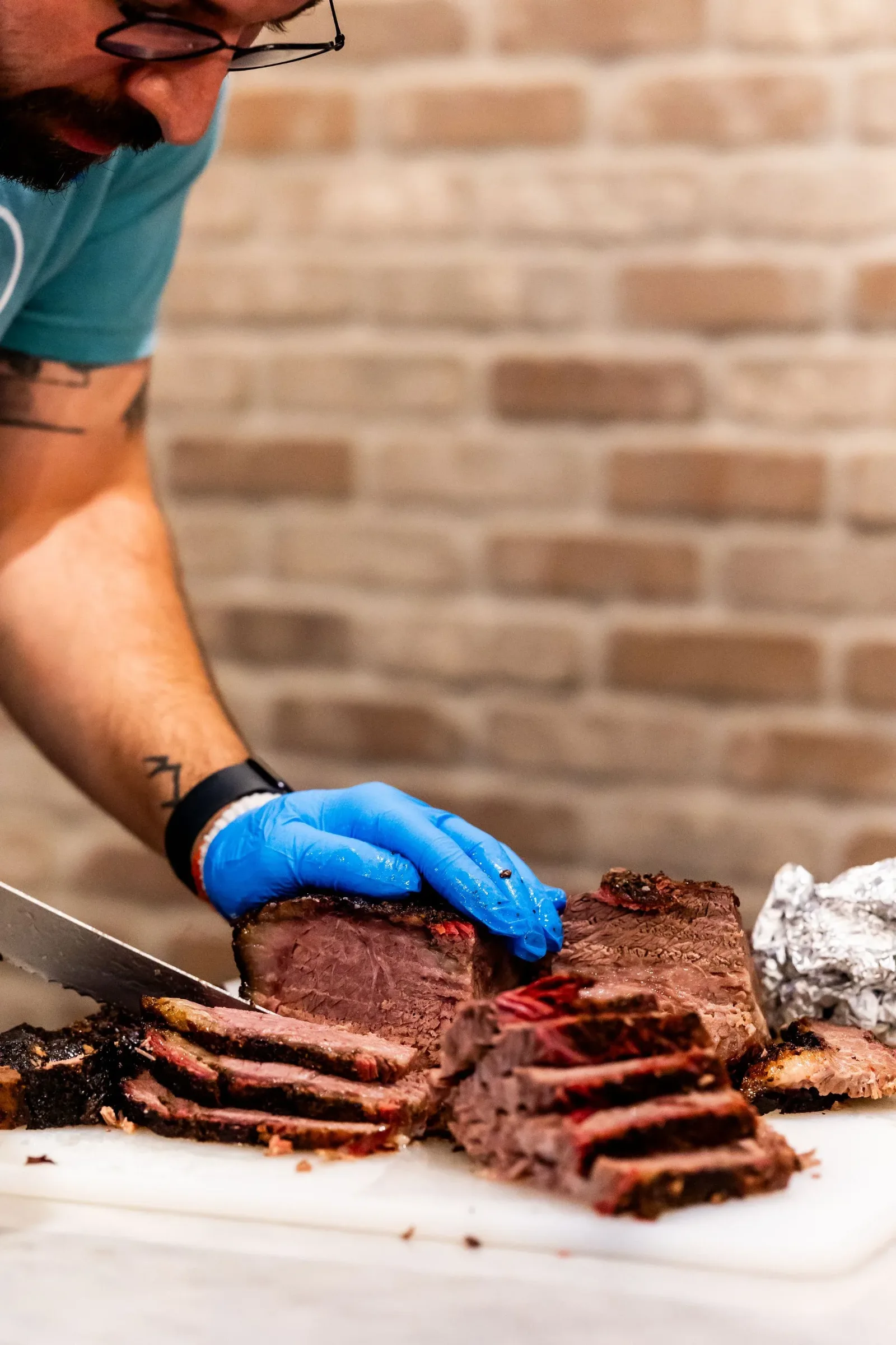 A gloved hand lifting a whole smoked brisket