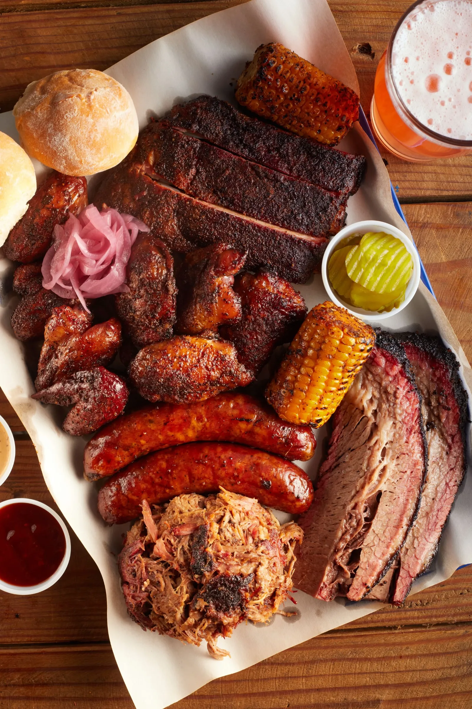 A plate of brisket, sausage and tacos with sides