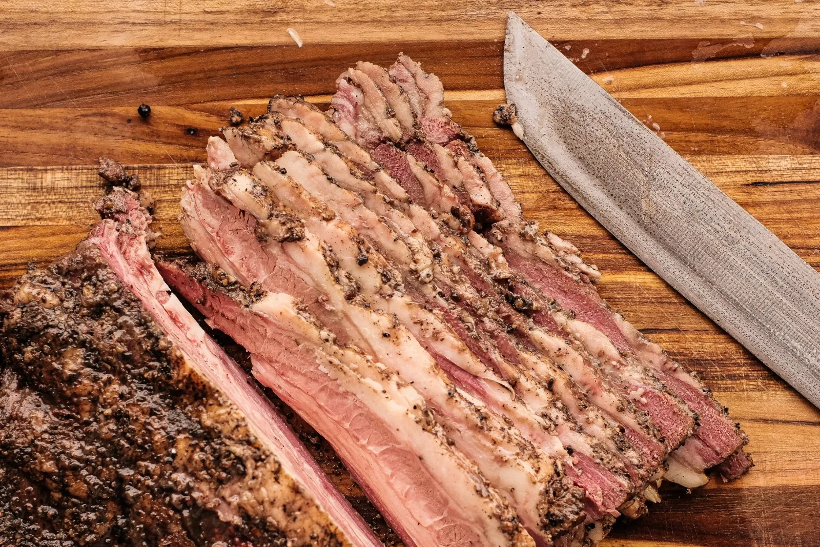 A whole smoked brisket sliced on the butcher block at Ember Meridian
