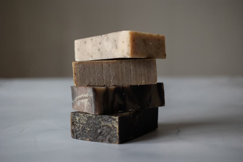 Four handmade soap bars stacked on a grey table