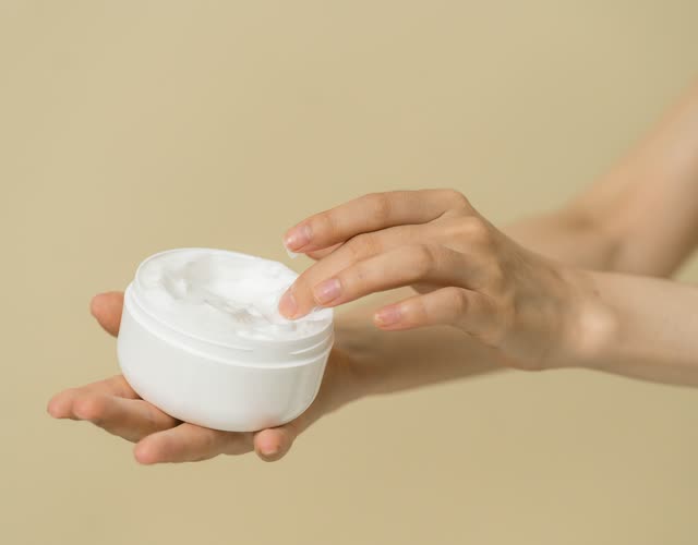 Hands holding an open jar of cream