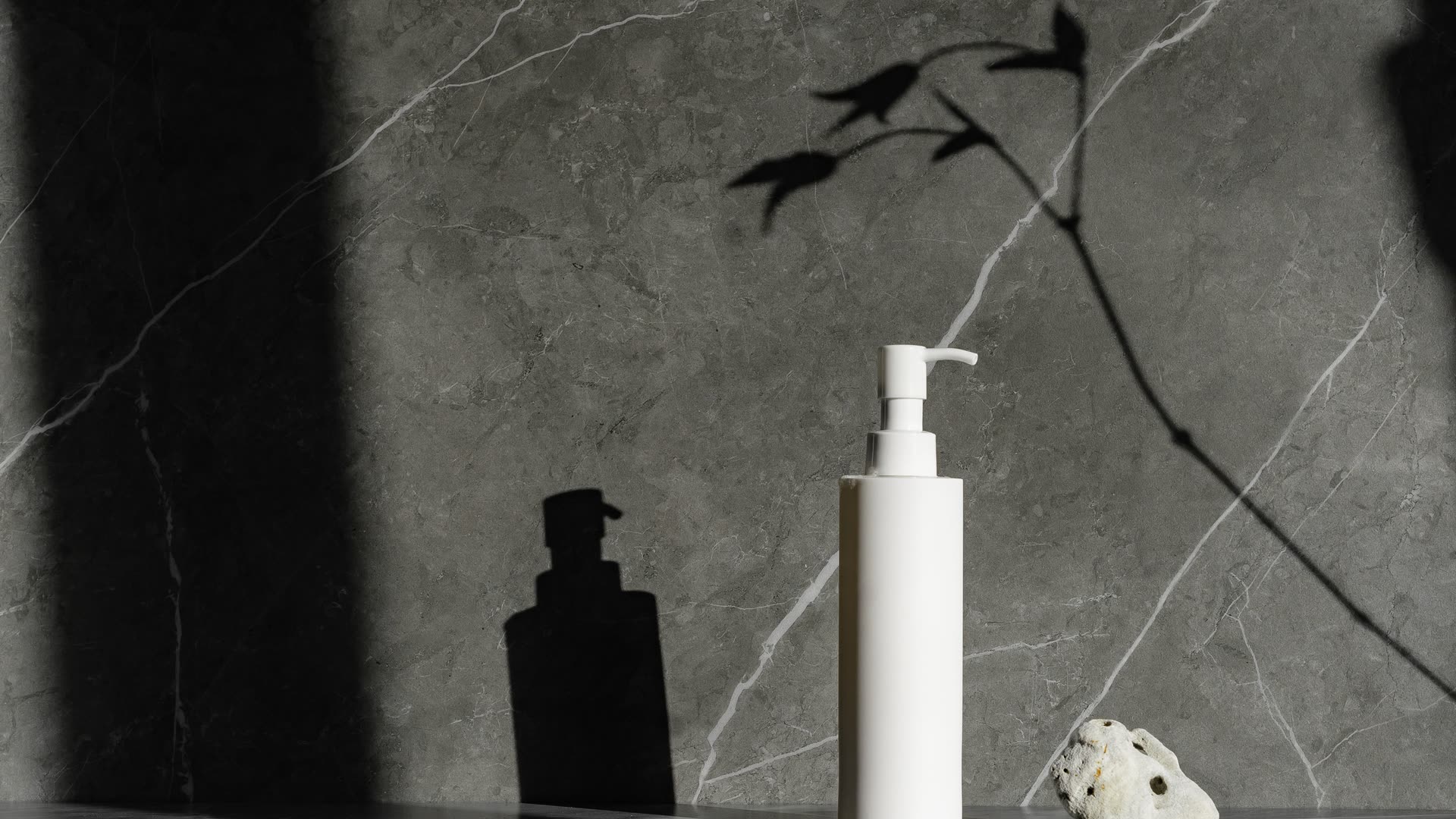 White pump bottle against a dark marble wall