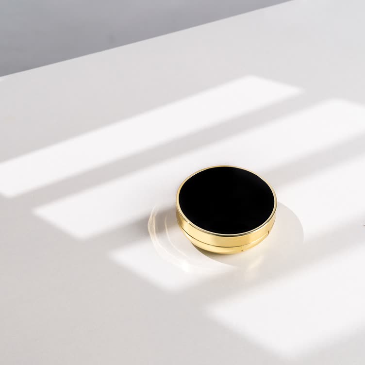 Round black-and-gold container on a white table