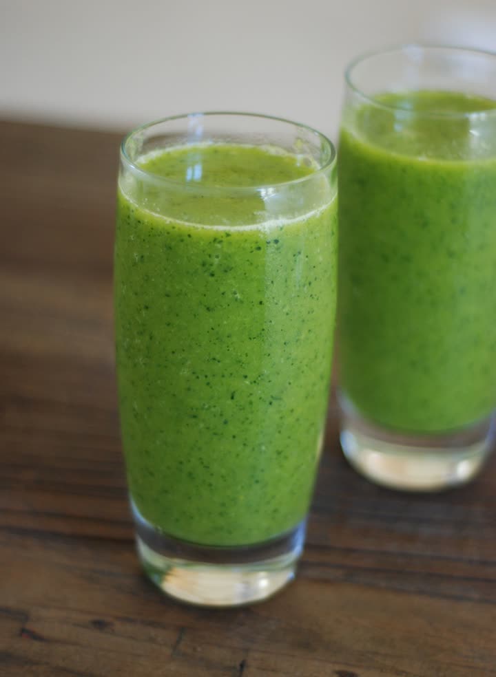 Two glasses of green smoothie on a wooden table