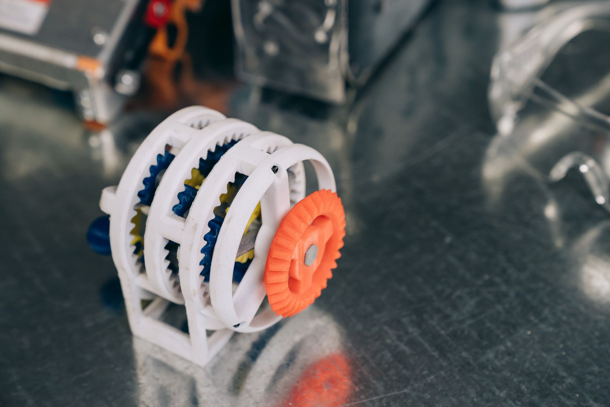 A printed gear-train model on a steel table