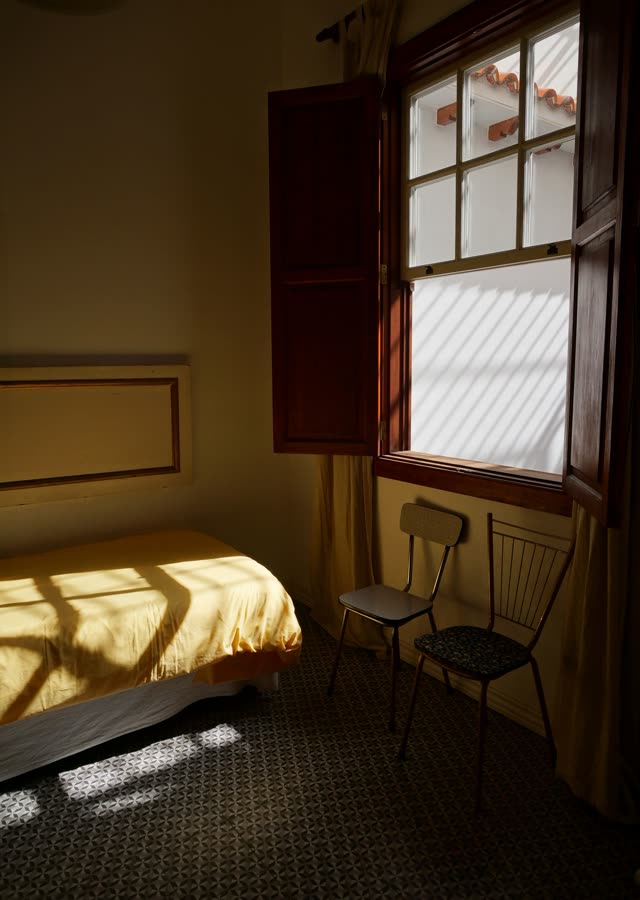 Late sun through a tall window across a made bed