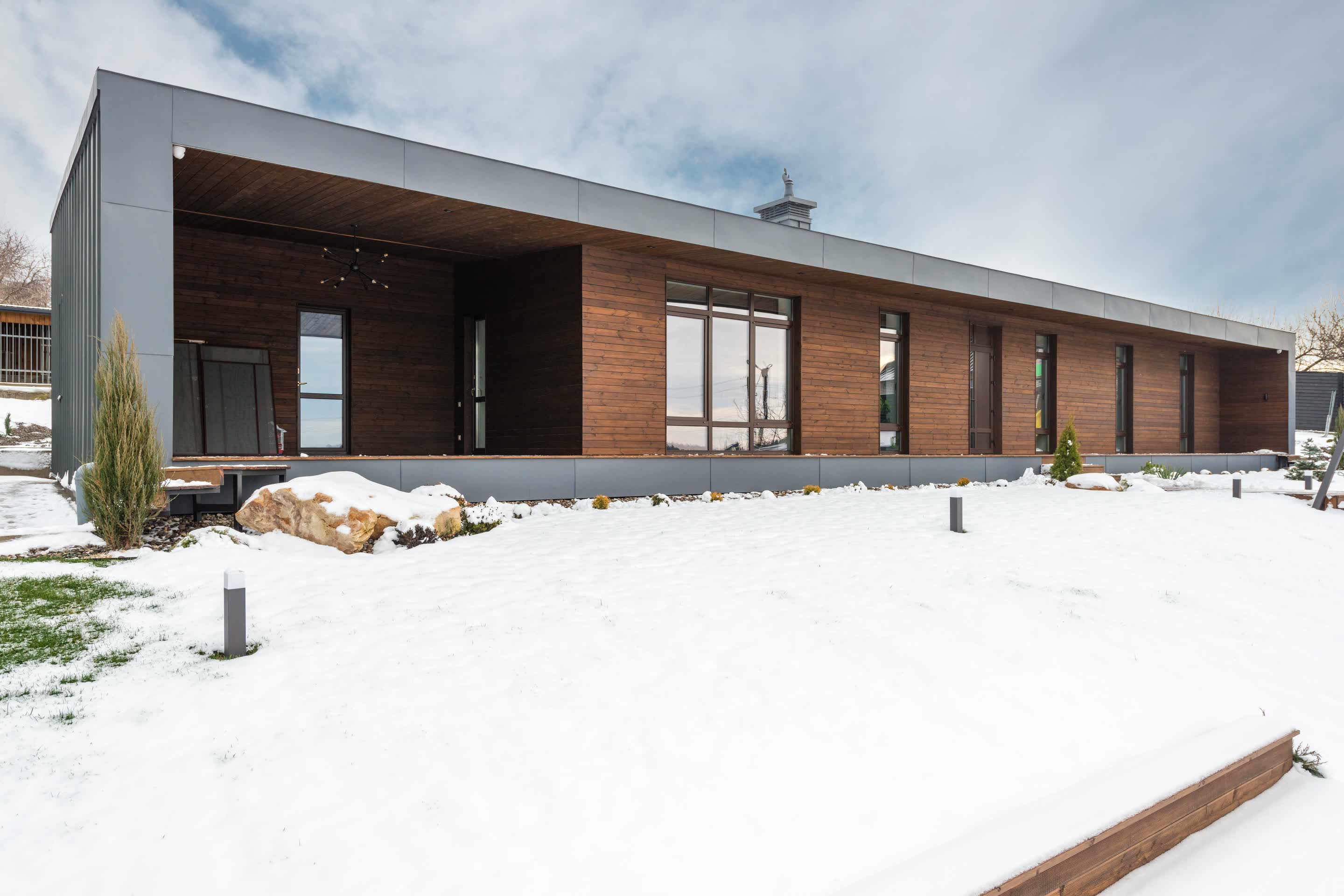 雪の庭に面した木張りの平屋の外観