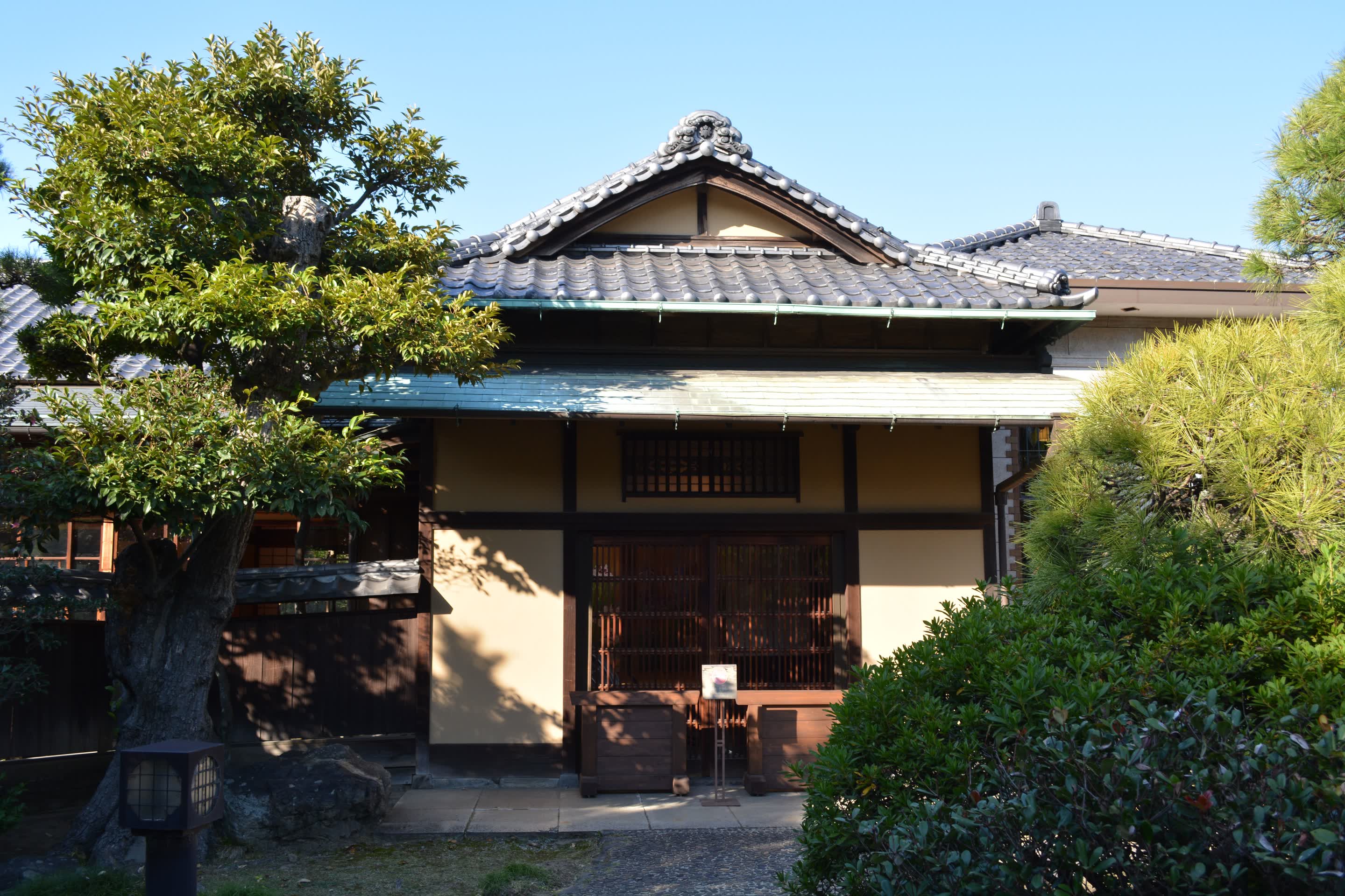 庭木に囲まれた瓦屋根の木造住宅