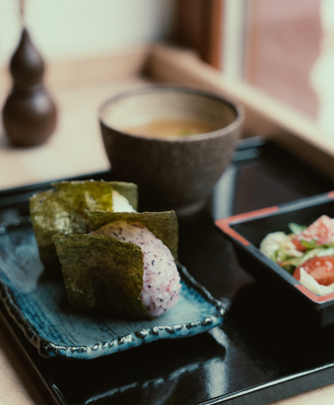 黒い膳にのったおにぎりと汁物