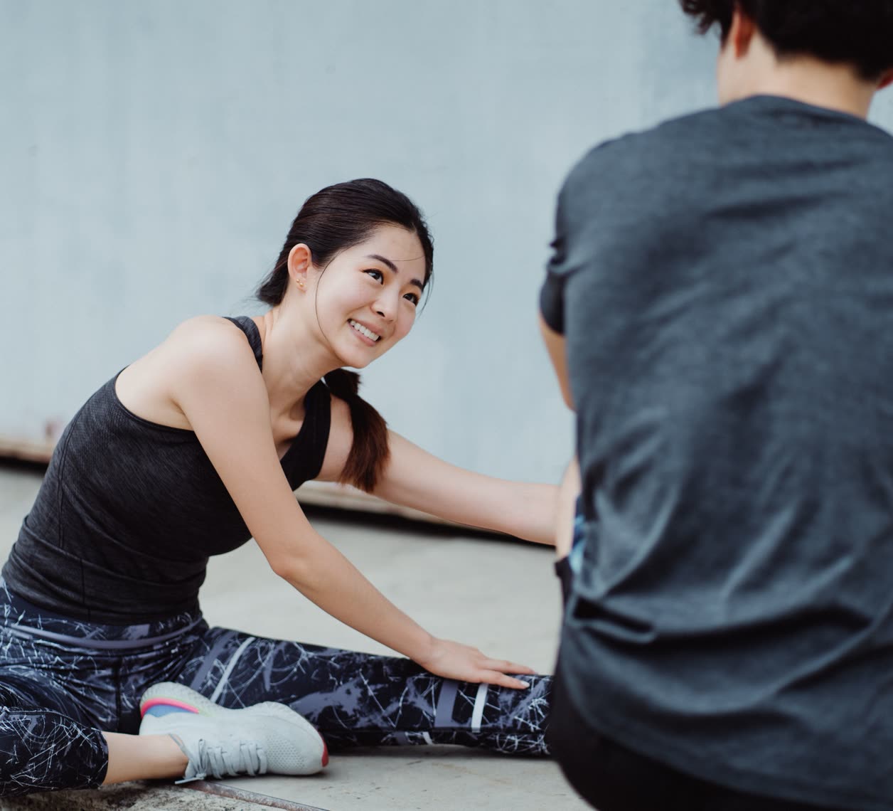 床に座ってストレッチをする会員と、そばで見るトレーナー