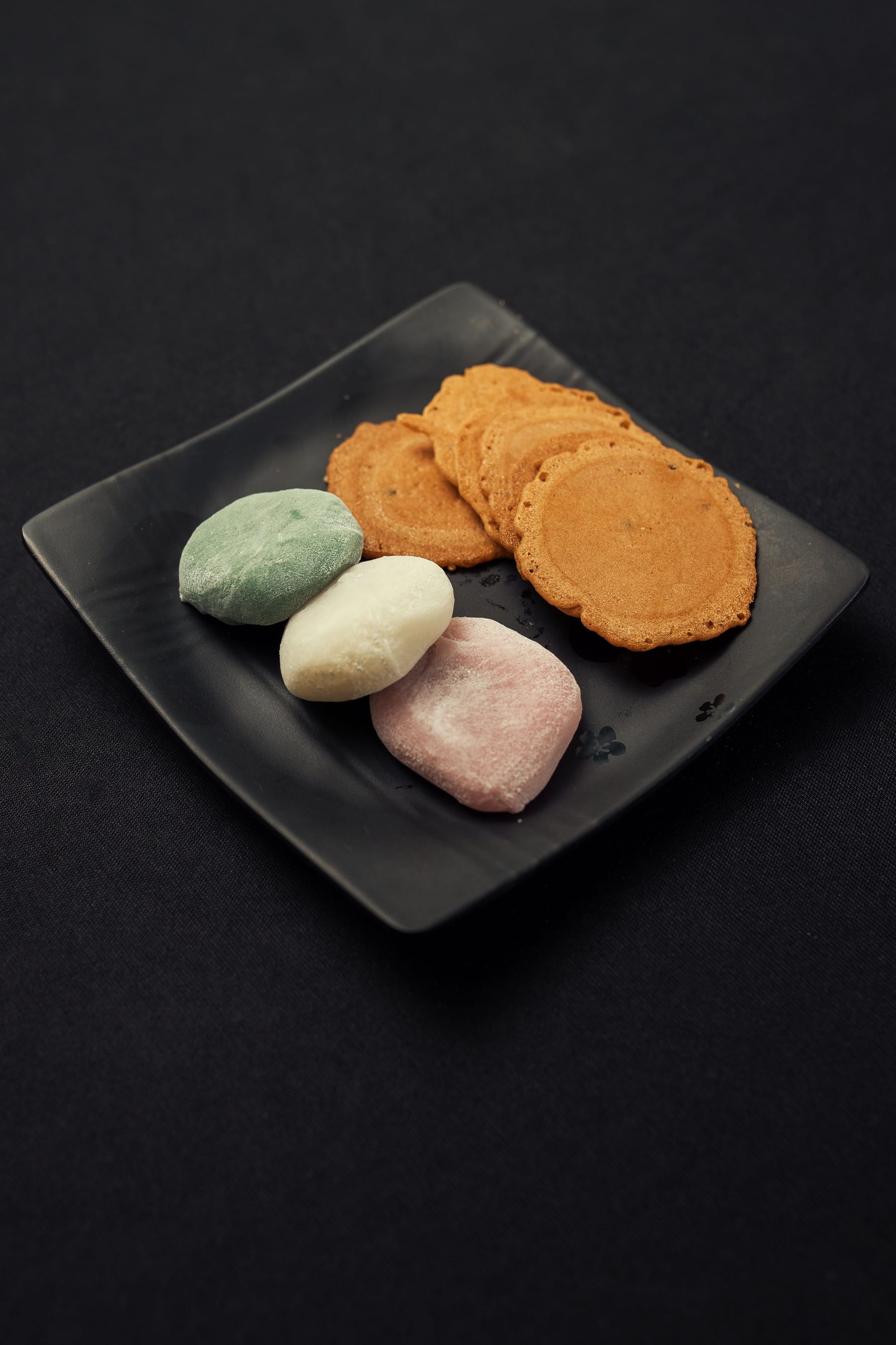 黒い皿に並べた干菓子と生菓子