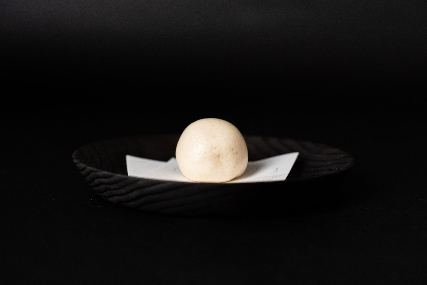 黒い器の紙の上にのせた白い蒸し菓子
