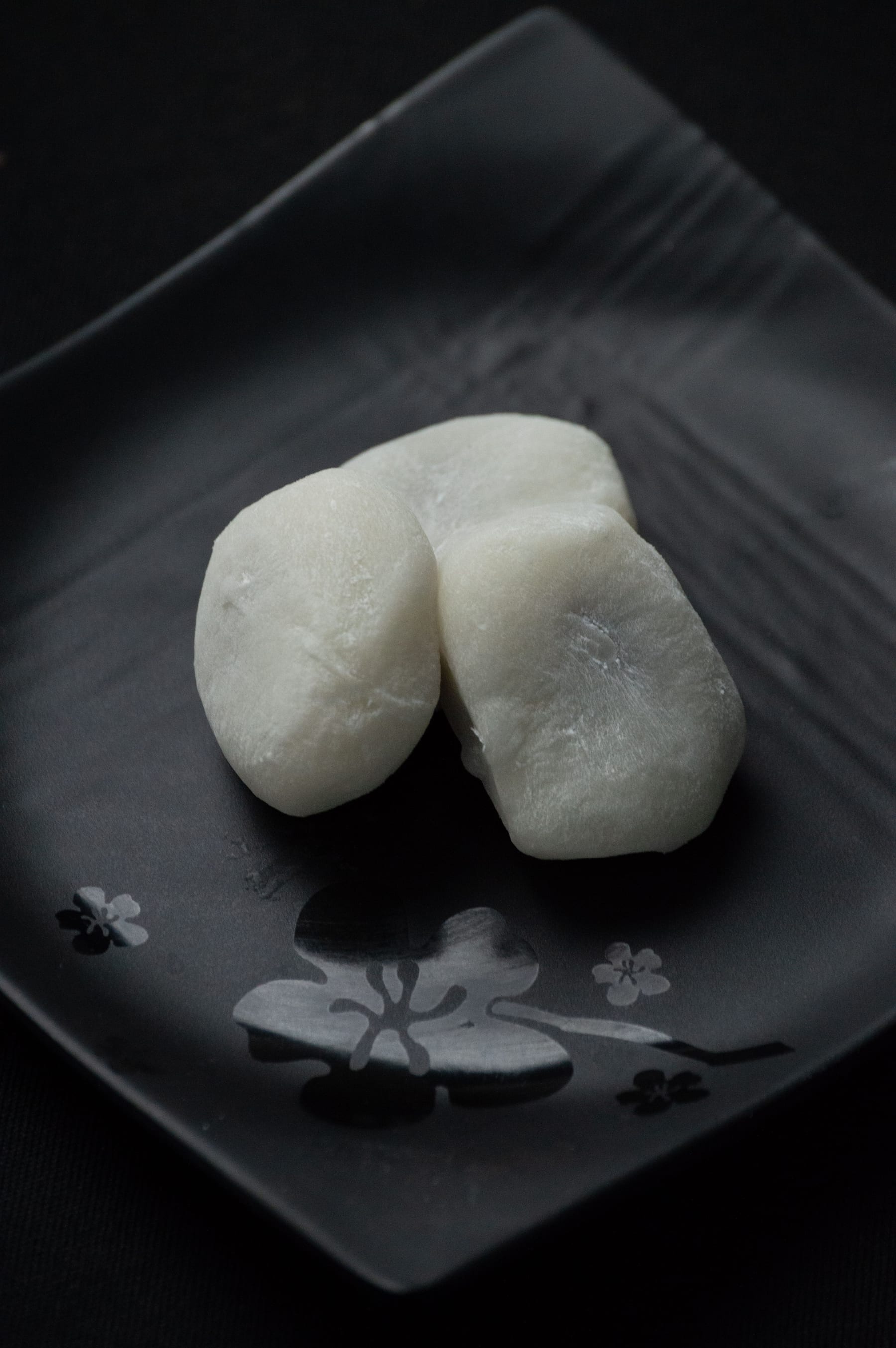 黒い皿にのせた白い生菓子