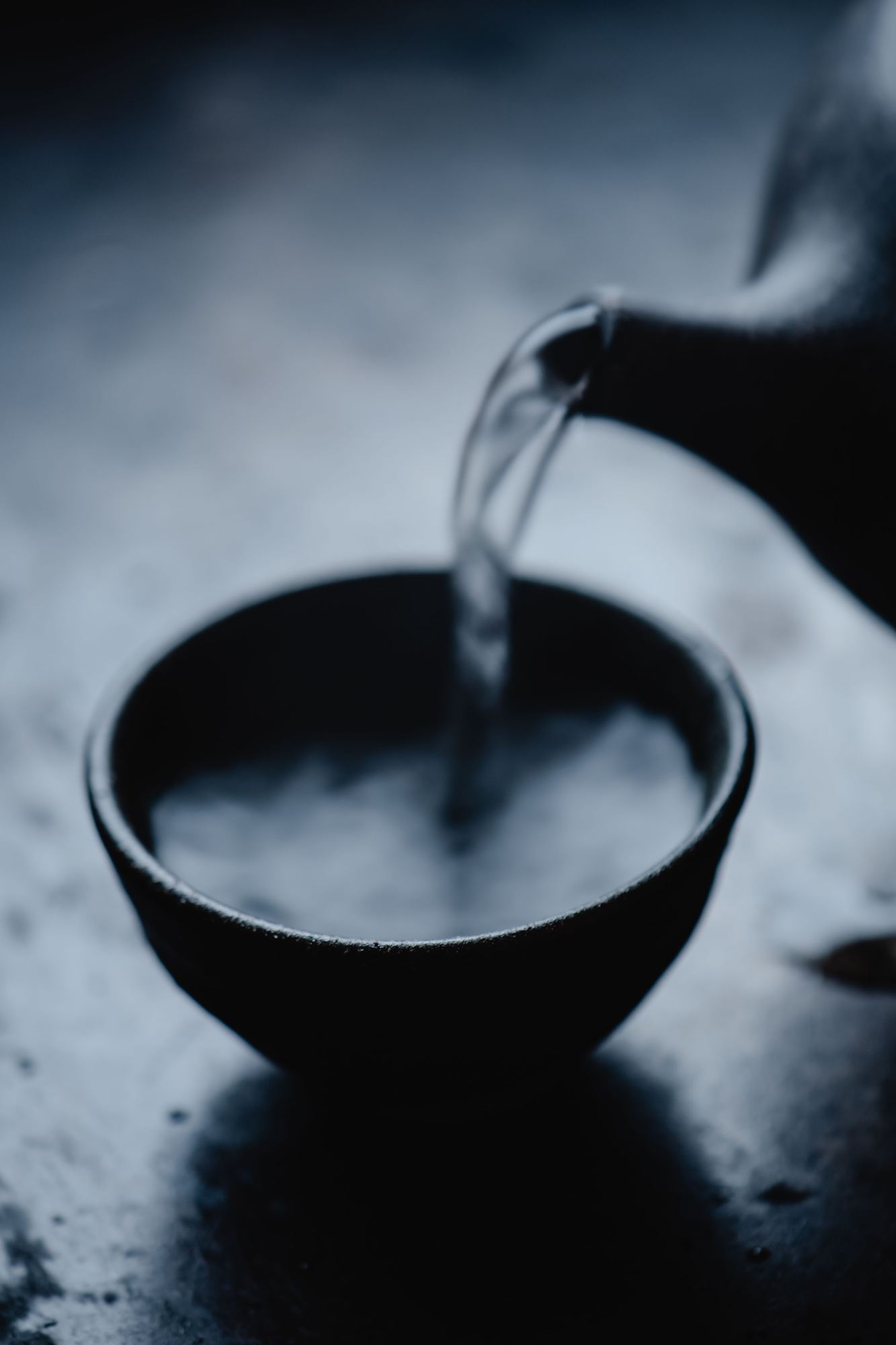 黒い椀に細く注がれている澄んだ酒