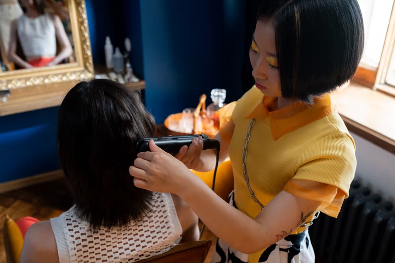 鏡の前で客の髪を整えるスタイリスト