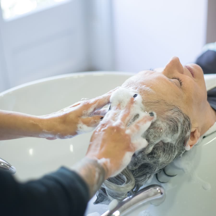シャンプー台で泡を立てて洗う手元