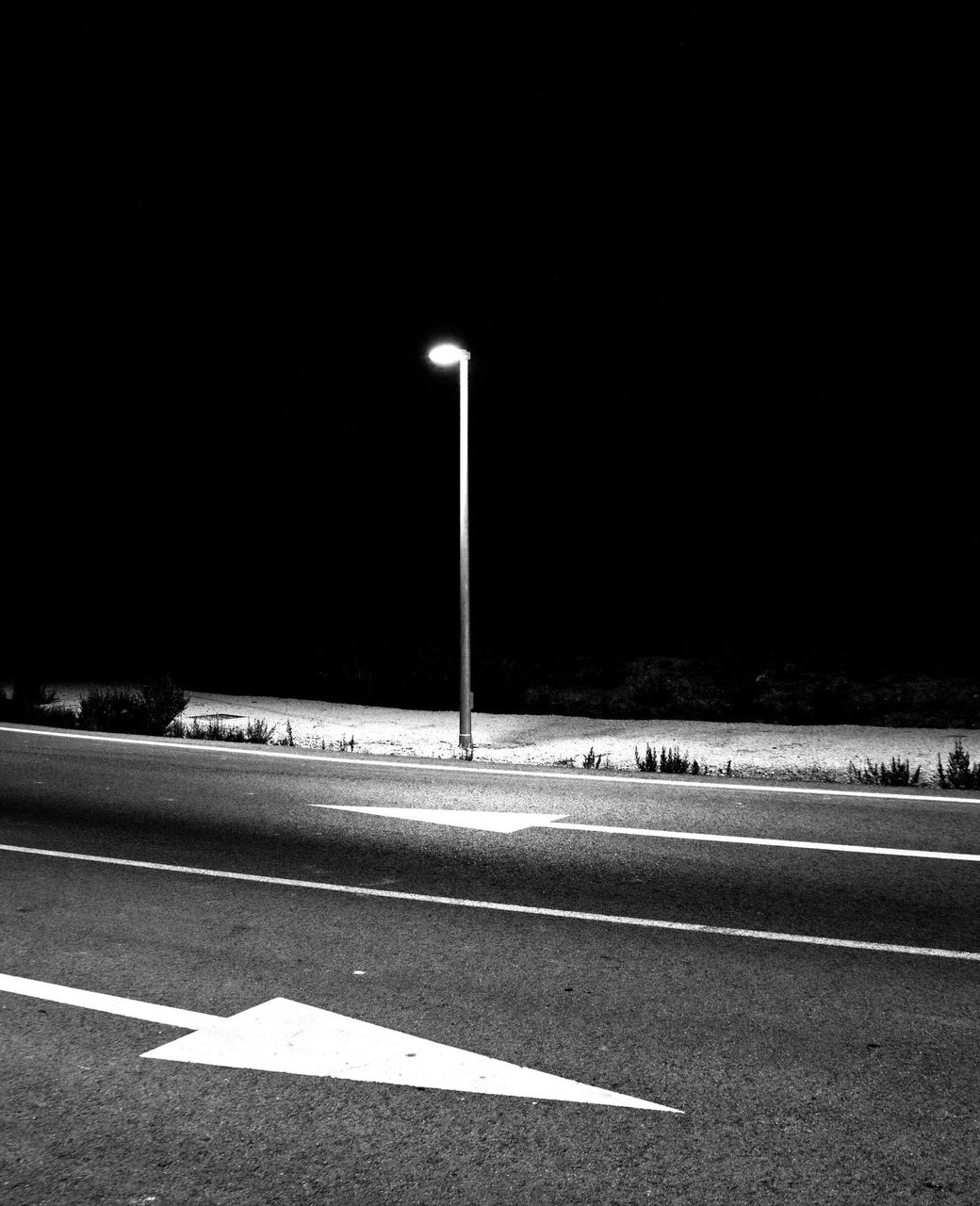 街灯だけが照らす夜の道路と路面の矢印