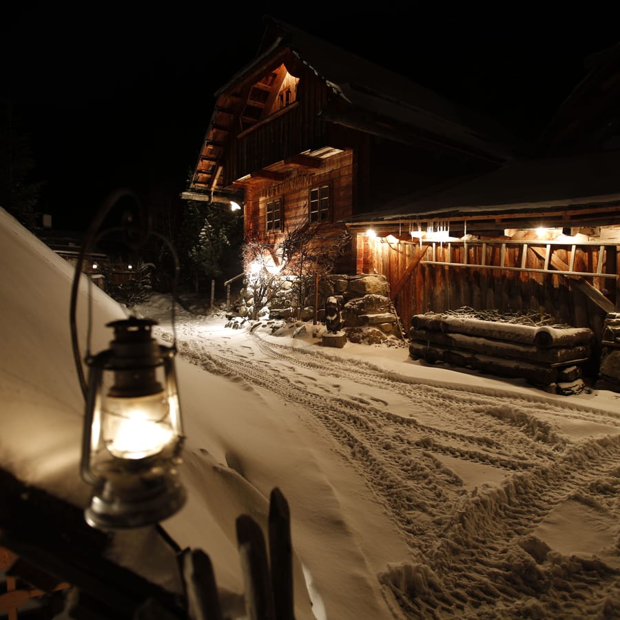 夕方、ランタンの明かりがともる雪の小屋
