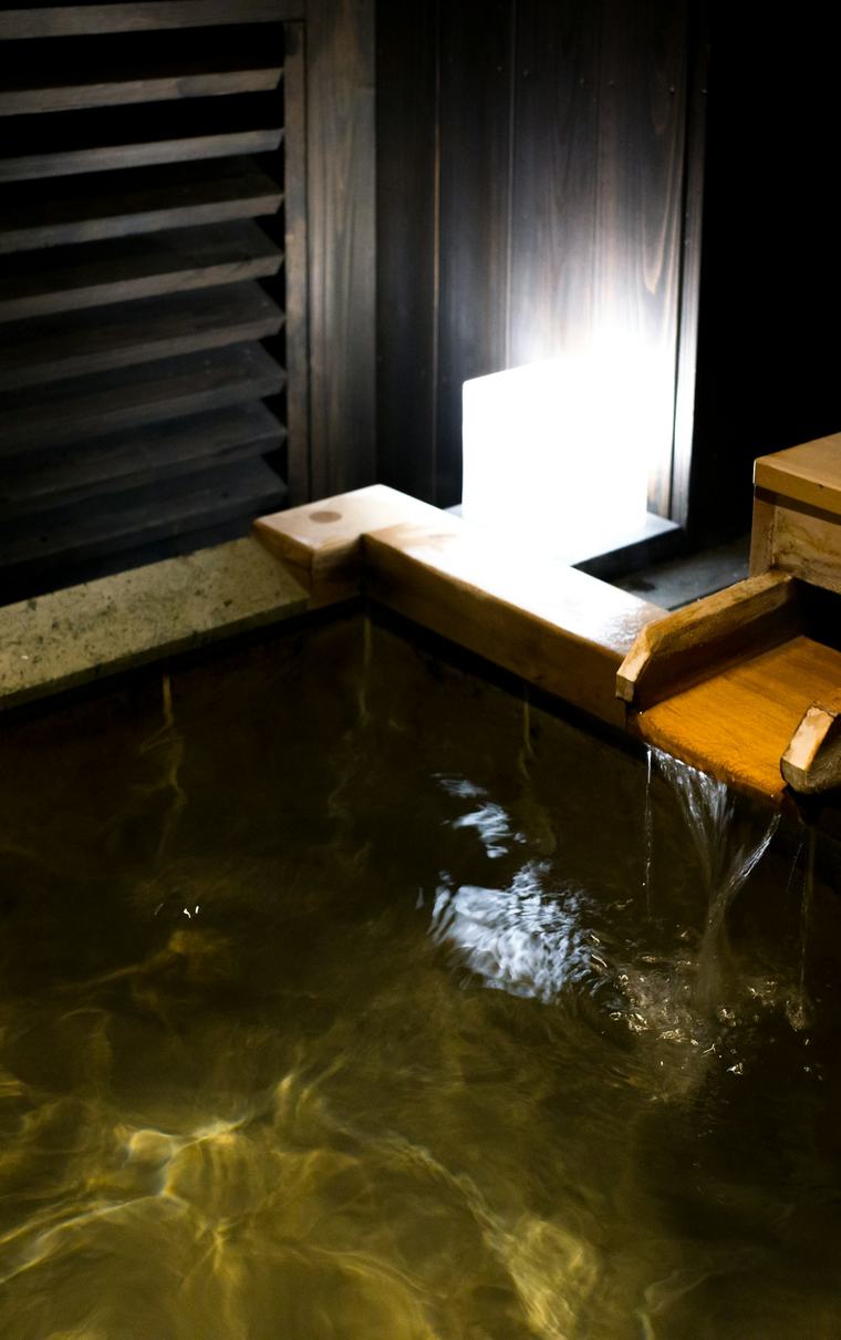 木づくりの内湯。湯口から湯が落ちている。