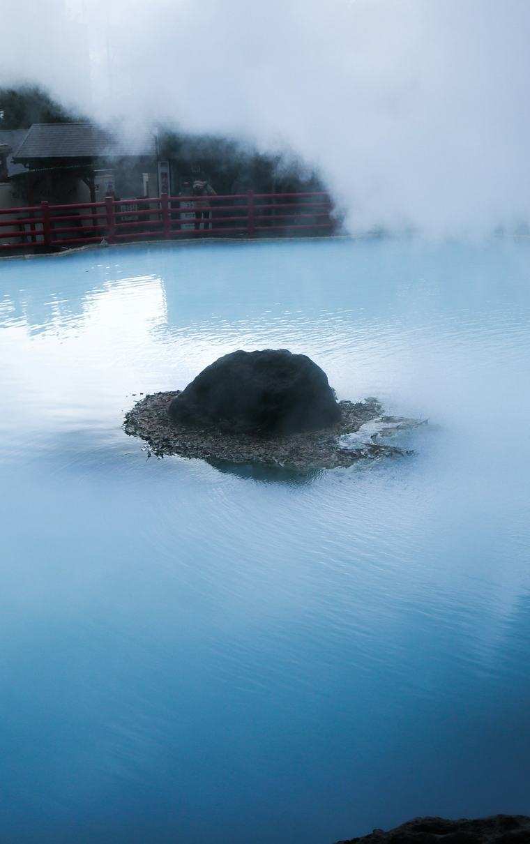 湯けむりの立つ湯面と、中ほどに置かれた石。
