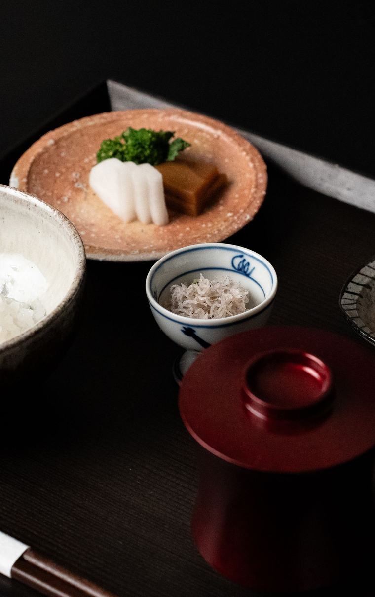黒い膳に並べた小鉢とご飯。