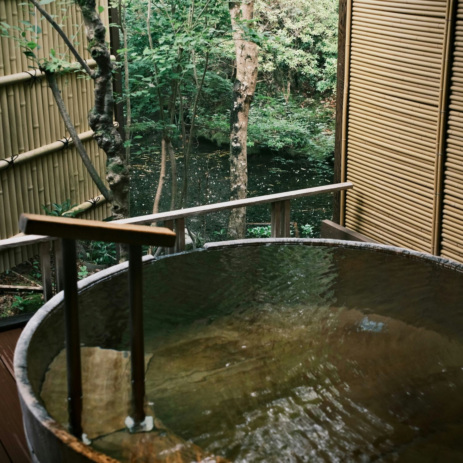 客室の露天風呂。木の湯船の向こうに林が見える。