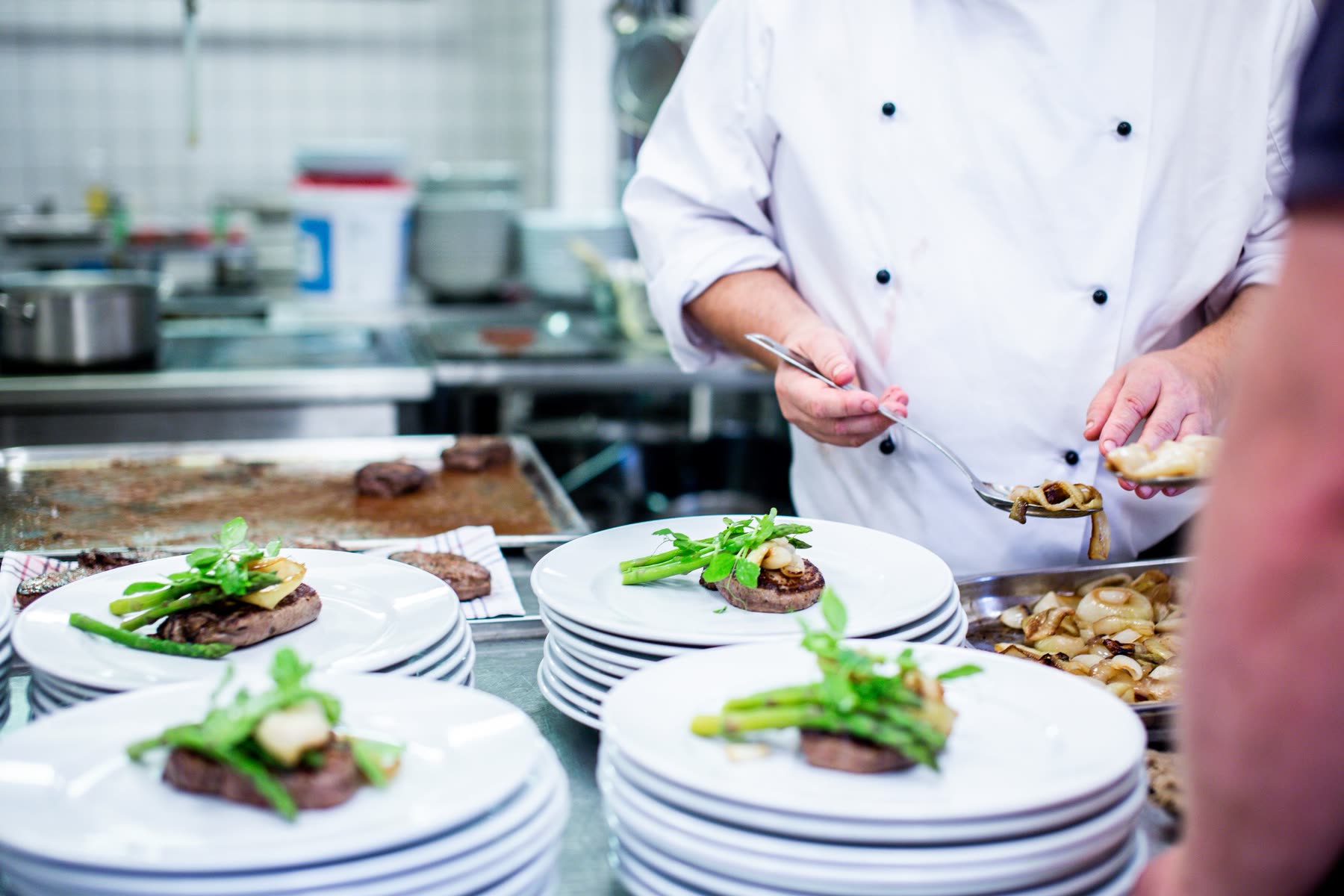 A cook finishing a row of plates at the pass