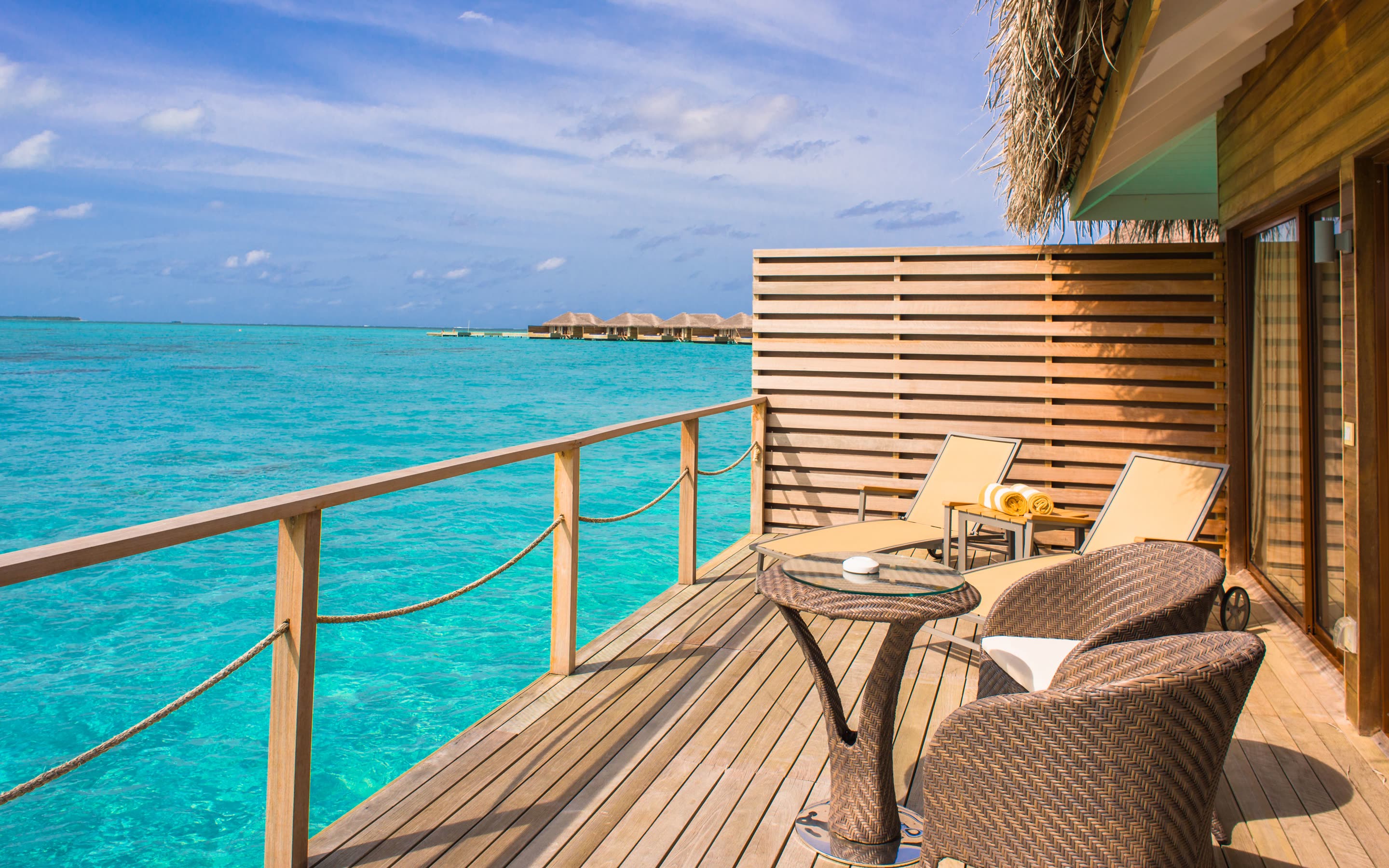 Wooden villa deck with lounge chairs over turquoise water