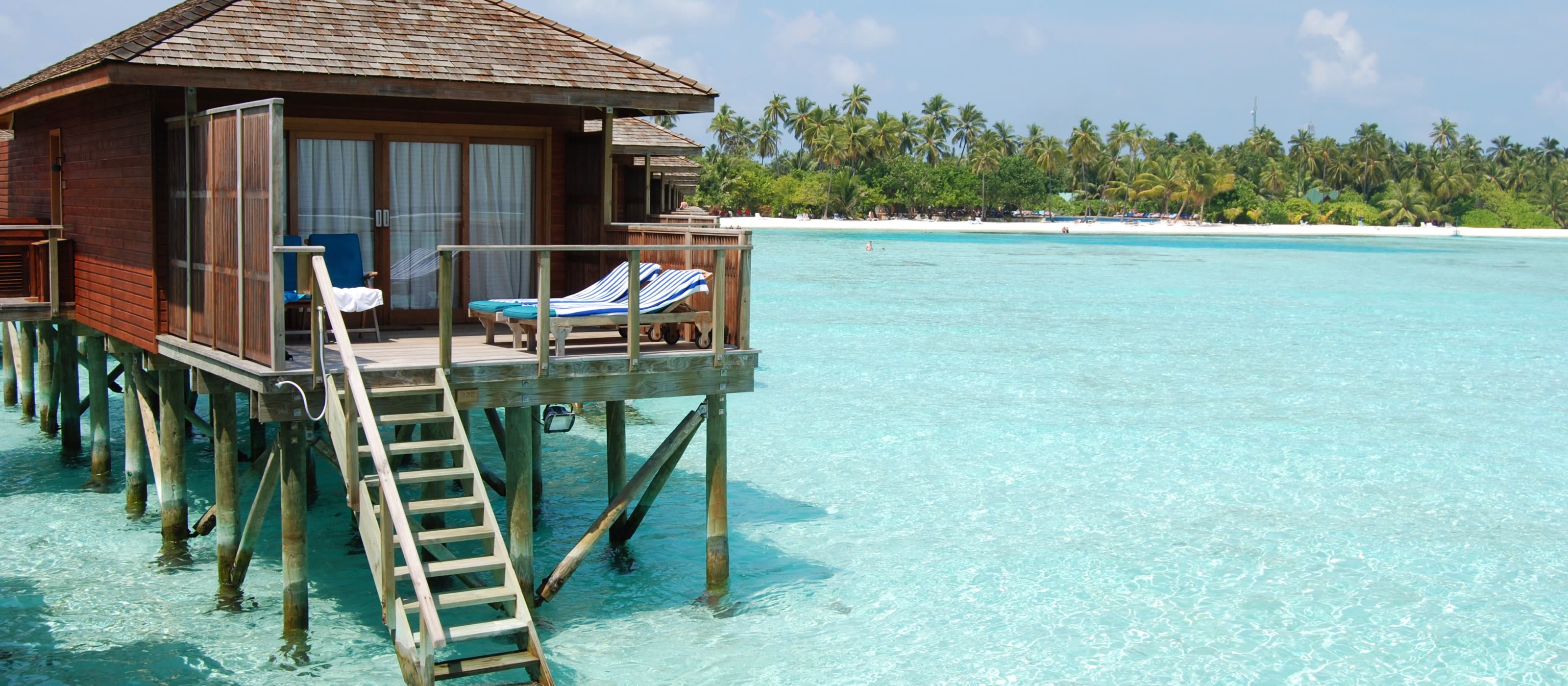 Water villa on pilings with a wooden ladder down into shallow clear water