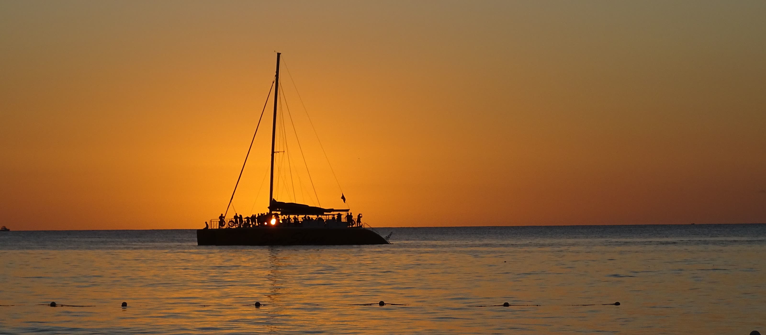 Catamaran silhouetted against an orange sunset sky