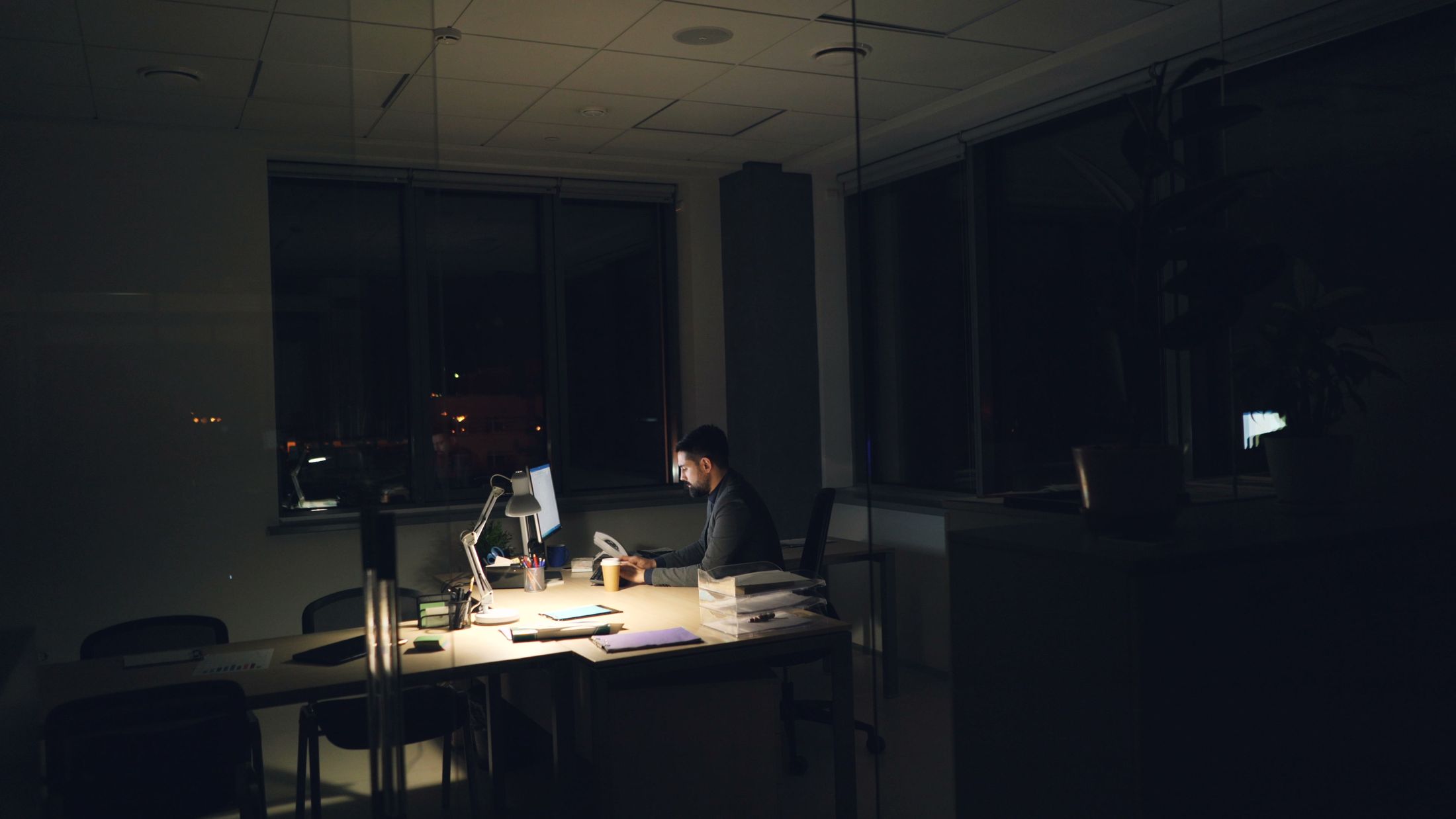 An office at night with one desk lamp on
