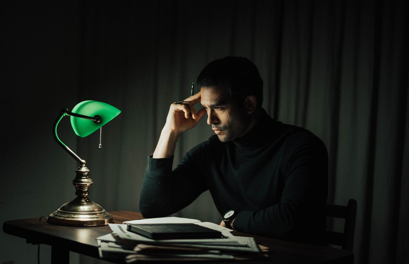A man reading files under a desk lamp
